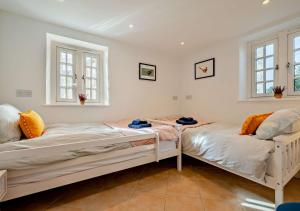 duas camas num quarto com duas janelas em Pearl Cottage - St Agnes em St. Agnes 