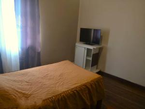 Dormitorio pequeño con cama y TV en La Casa Discreta Cochabamba, en Cochabamba