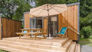 a tiny house with an umbrella and a wooden deck at Camping Etennemare in Saint-Valery-en-Caux +11 photos