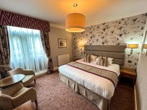 Habitación de hotel con cama y silla en Lodore Falls Hotel & Spa en Keswick