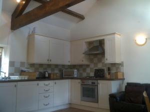 a kitchen with white cabinets and a stove top oven at Knotts Farm Holiday Cottages in Lancaster