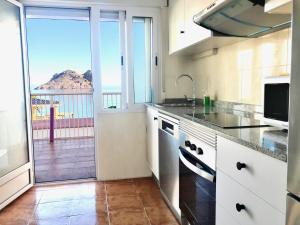 a large kitchen with a view of a balcony at La Paloma, Chalet a pie de playa in Águilas