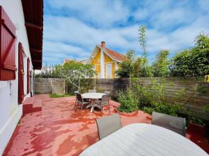 a patio with a table and chairs and a yellow house at Villa Arcachon, 4 pièces, 6 personnes - FR-1-433-69 in Arcachon