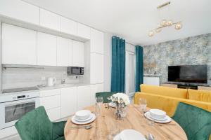 a kitchen and dining room with a wooden table and green chairs at Beautiful Apartment with Balcony & Free Garage by Renters in Poznań