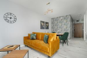 a living room with a yellow couch and a table at Beautiful Apartment with Balcony & Free Garage by Renters in Poznań