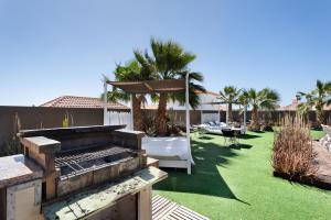a backyard with a grill and a lawn with palm trees at Villa Golf del Sur in San Miguel de Abona