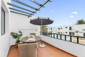 a balcony with a table and an umbrella at Gara Apt Puerto del Carmen in Tías