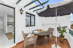 a dining room with a table and chairs and an umbrella at Gara Apt Puerto del Carmen in Tías