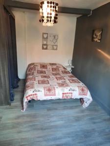 a bedroom with a bed with a red and white quilt at LE CHANT DE LA RIVIERE in Sainte-Marie-aux-Mines