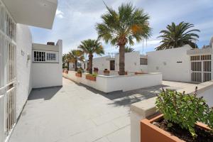 een binnenplaats met palmbomen en een wit gebouw bij Aaron Beautifull House in Arona