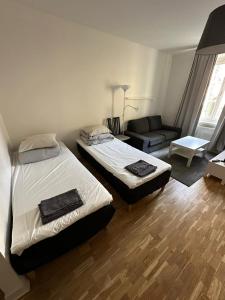 two beds in a small room with a couch and a room with at Home Inn RSG19 in Stockholm