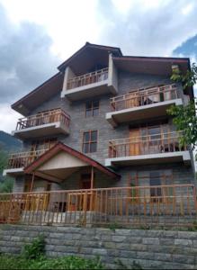 a large building with balconies and a fence at heavens retreat manali in Manāli