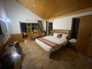 a bedroom with a bed and a table and windows at heavens retreat manali in Manāli