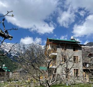 an old building with mountains in the background at heavens retreat manali in Manāli