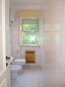La salle de bains blanche est pourvue de toilettes et d'une fenêtre. dans l'établissement 244 - Villa singola quadrilocale al Taunus con ampio giardino e garage, à Numana