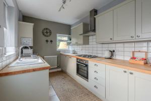a kitchen with white cabinets and a sink at Entire 2-bedroom house with garden in York