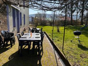 un patio con mesa, sillas y parrilla en Aux 2 cerisiers, en Virton