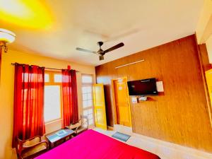 a bedroom with a pink bed and a tv at Grand view lodge and Restaurant Dharamshala - Partial Prepayment required to confirm booking in Dharamshala