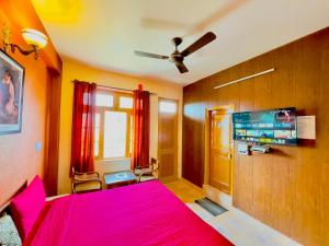 a bedroom with a pink bed and a flat screen tv at Grand view lodge and Restaurant Dharamshala - Partial Prepayment required to confirm booking in Dharamshala