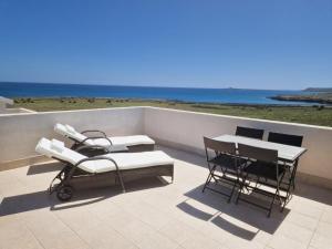 um pátio com uma mesa e cadeiras e o oceano em Affittimoderni - Marzamemi Luxury Residence em Marzamemi