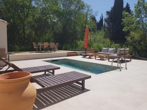a patio with a pool with benches and chairs at Villa st Francois Piscine privée chauffée ,clim ,parking gratuit in Carcassonne