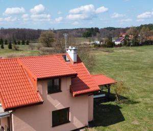 een huis met een oranje dak en een veld bij Mazury Apartament/Dom z ogródkiem całoroczny przy jeziorze in Sędańsk