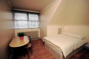 1 dormitorio con cama, mesa y ventana en 24/7 London Hostel, en Londres