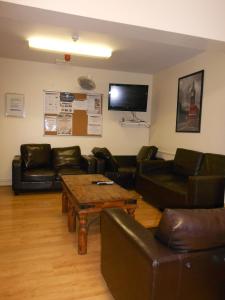 sala de estar con muebles de cuero y TV de pantalla plana en 24/7 London Hostel, en Londres