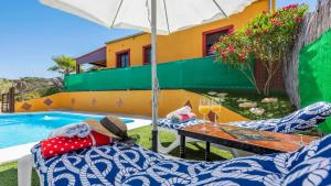 a patio with two chairs and an umbrella next to a pool at Casa Gonzalez Villanueva de la Concepcion by Ruralidays in Villanueva de la Concepción