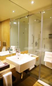 y baño con lavabo blanco y ducha. en Marasa Sarovar Portico -Rajkot, en Rajkot