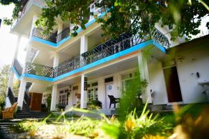 a large white building with blue trim at Hostelgia in Manāli