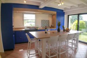 eine Küche mit blauen Wänden sowie einem Tisch und Stühlen in der Unterkunft Beautiful villa with heated indoor pool, large garden close to beach, 8 people in Moëlan-sur-Mer