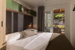 1 dormitorio con 1 cama blanca grande y balcón en Mobile Homes Lopari en Nerezine