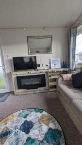 a living room with a flat screen tv and a fireplace at Superb 8 Berth Caravan At Steeple Bay Holiday Park, Essex Ref 36039f in Southminster