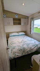 een bed in een kleine kamer met een raam bij Superb 8 Berth Caravan At Steeple Bay Holiday Park, Essex Ref 36039f in Southminster