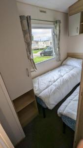 a small bedroom with two beds and a window at Superb 8 Berth Caravan At Steeple Bay Holiday Park, Essex Ref 36039f in Southminster