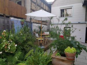 un patio con una mesa con sombrilla y plantas en Charmantes Zimmer mit Bad im Stadtzentrum, en Pottenstein