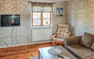 sala de estar con sofá, TV y silla en Amazing Home In Ronneby With Kitchen, en Ronneby