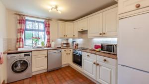 a kitchen with white cabinets and a washer and dryer at Wye Cottage near Hassop in Eyam