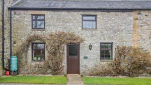 a stone house with a brown door and windows at Wye Cottage near Hassop in Eyam