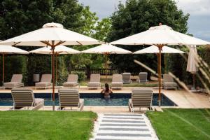 a woman sitting in a pool with chairs and umbrellas at Château de Noizay - ChâteauZen in Noizay