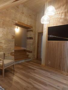 ein Wohnzimmer mit einem TV, einem Sofa und einem Stuhl in der Unterkunft GITE Le grenier du Jean 8 personnes in Sancey-le-Long