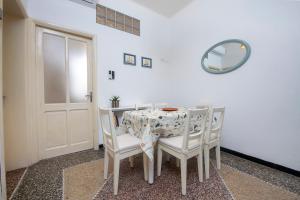 - une table à manger avec des chaises blanches et un miroir dans l'établissement 244 - Casa Ludo, Centro Storico,140m dalla Baia del Silenzio PATRIMONIO UNESCO spiaggia e mare, à Sestri Levante