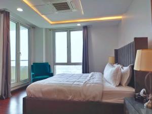 - une chambre avec un grand lit et une chaise bleue dans l'établissement One bed appartment in GOLDCrest DHA Lahore, à Lahore