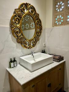 een badkamer met een witte wastafel en een gouden spiegel bij Honeymoon Guesthouse in Ubud
