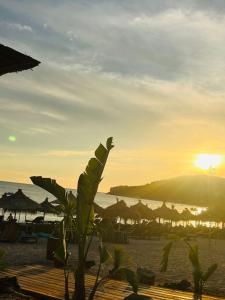 - un coucher de soleil sur une plage avec des parasols et l'océan dans l'établissement Hotel Billy, à Himarë