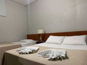 Dos camas en un dormitorio con toallas. en Hotel Ouro Verde, en Três Pontas