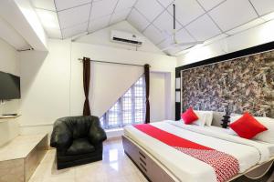 1 dormitorio con 1 cama grande y 1 silla en OYO Nova Dumas Homestay, en Surat