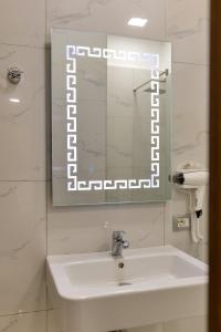uma casa de banho branca com um lavatório e um espelho em Hotel Billy em Himare