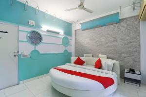 a bedroom with a large white bed with red pillows at OYO Nova Dumas Homestay in Surat